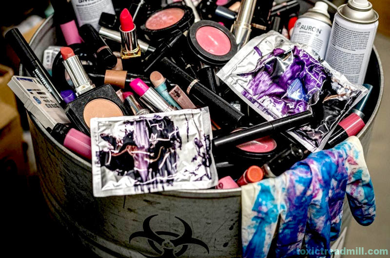 A metal drum with a biohazard label, full of waste makeup and hair dye products